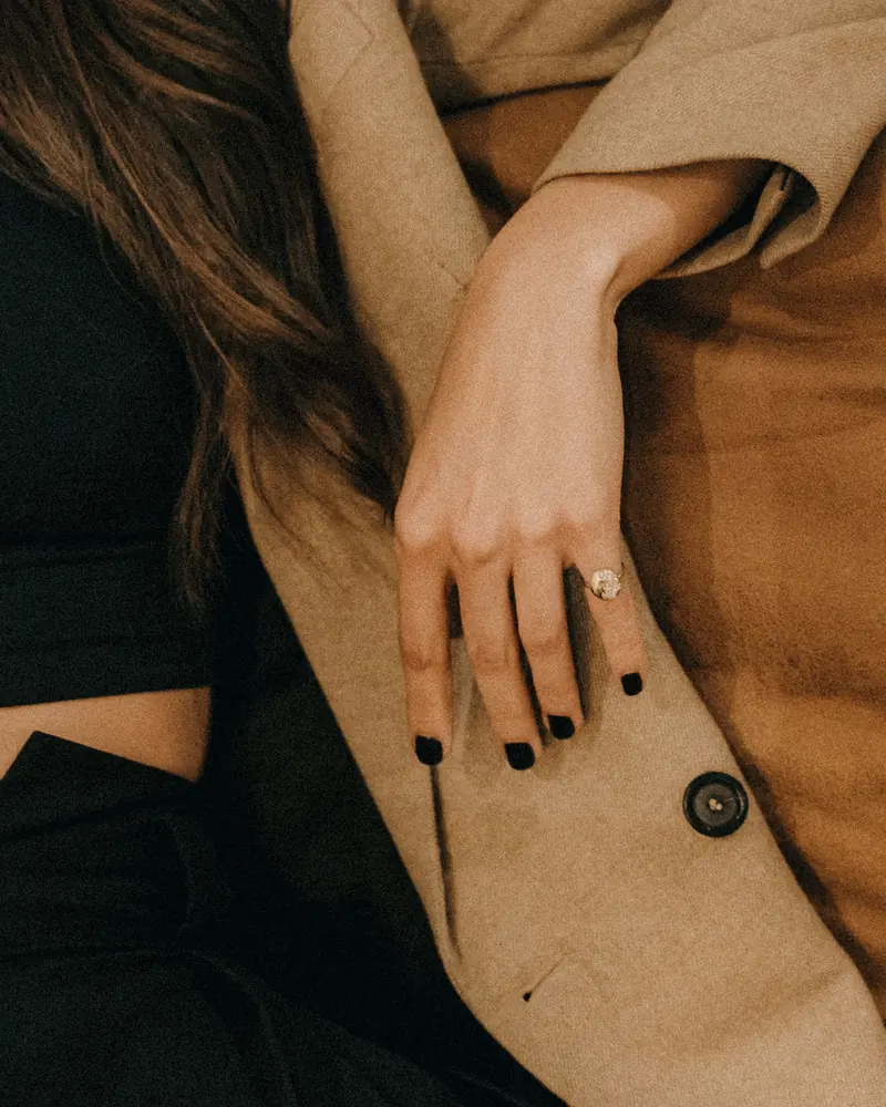 Faceted ring worn on a hand with a camel coat