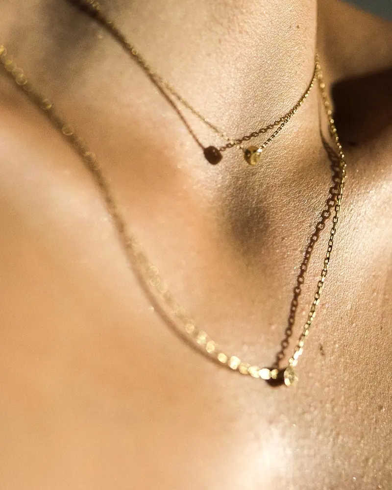 Layered delicate necklaces worn in warm light